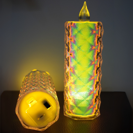 Two colorful, textured candles on a dark surface with a blurred background