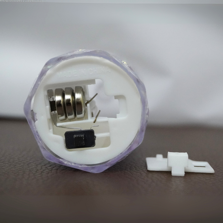 Close-up of a mechanical component with a spring and electronic parts on a blurred background