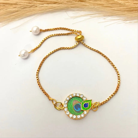 Gold bracelet with a peacock feather charm on a white background
